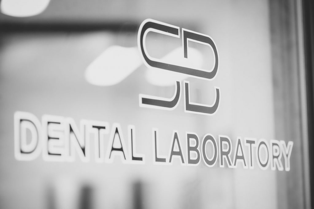The logo on the glass door of SB Dental Laboratories
